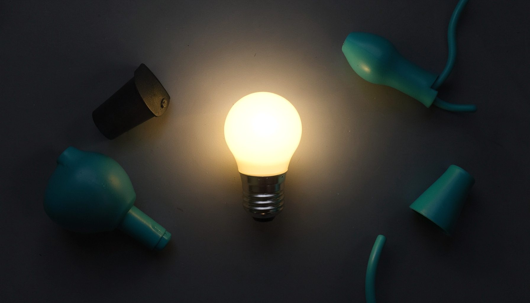 A warm white LED bulb glowing softly against a dark background, casting a gentle amber halo