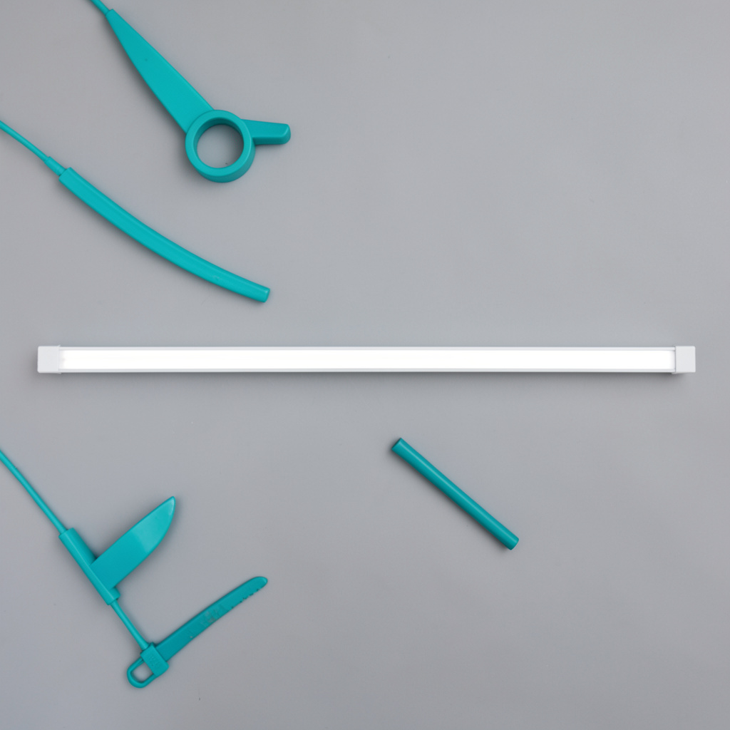 Overhead flat-lay photograph of a linear LED ceiling panel with a slim profile, cool white tones on a grey backdrop
